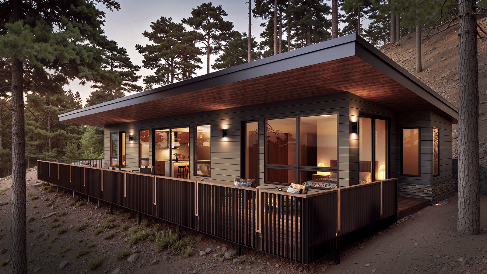 Modern cabin on a wooded hillside with a large deck, dark siding, and warm interior lights at dusk.