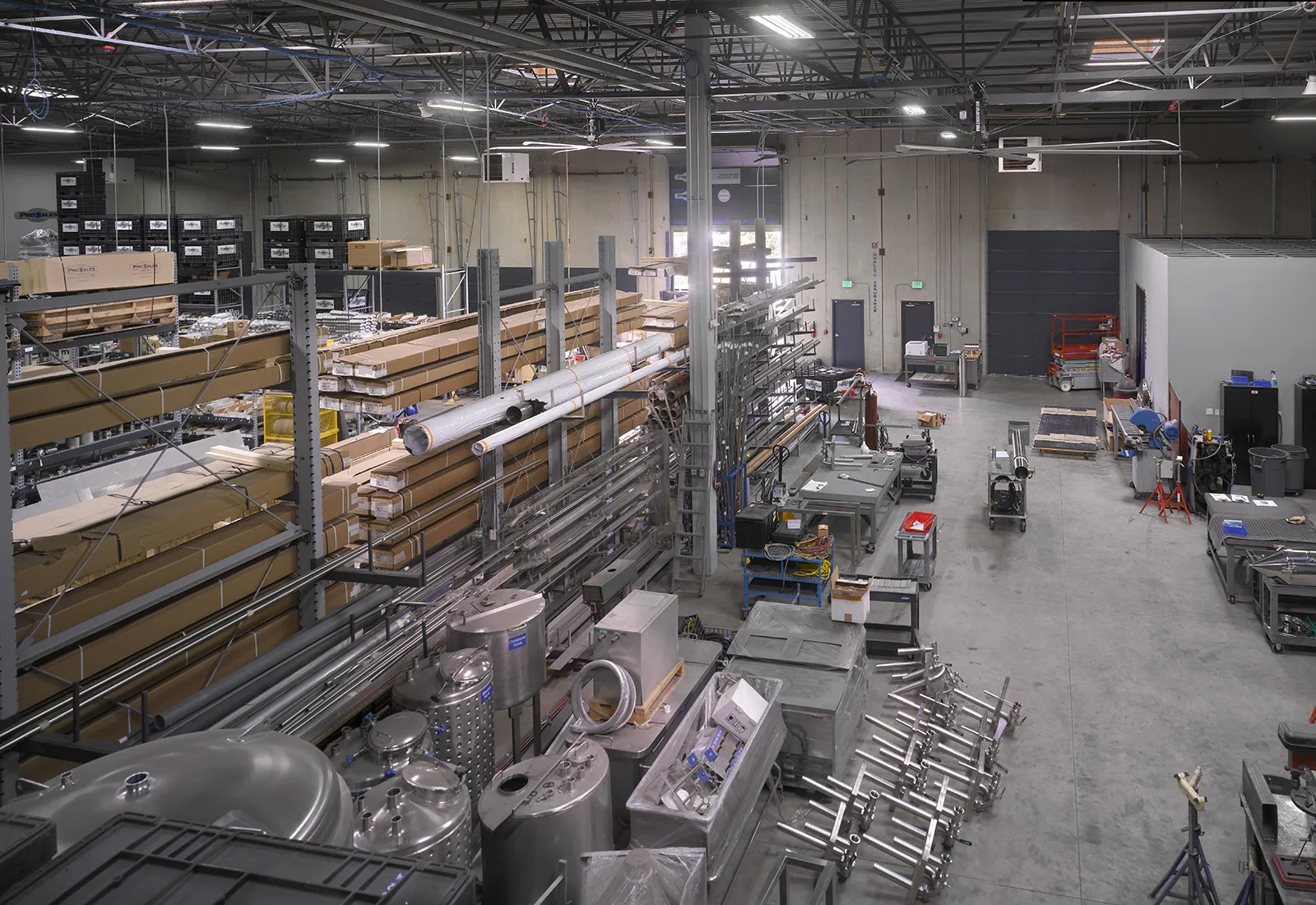 High-angle view of an industrial manufacturing facility with metal storage racks, steel pipes, and equipment.
