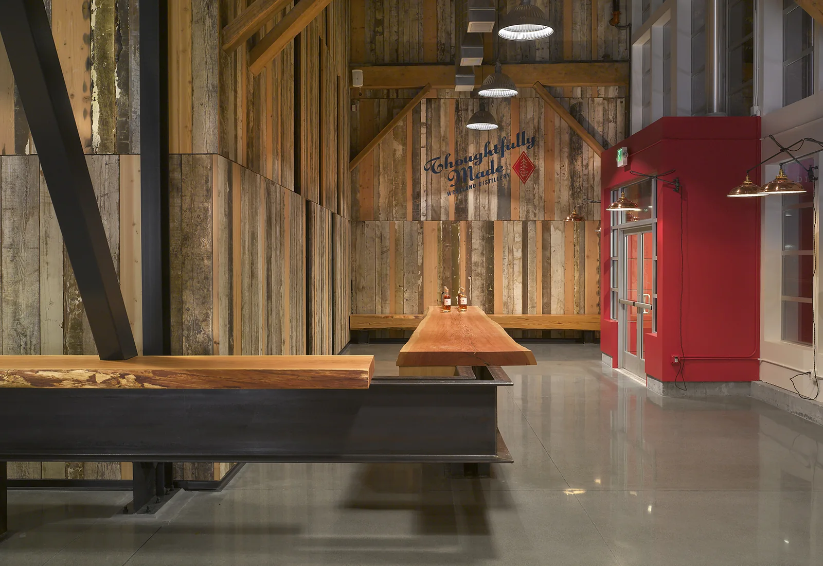 Industrial reception area with reclaimed wood walls, live-edge wood counters, and a vibrant red entryway.