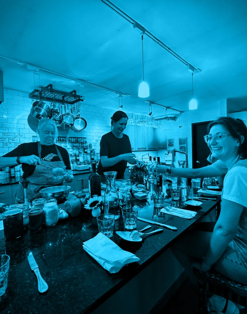 People preparing food around a kitchen counter during a team-building event, shown with a blue color filter.