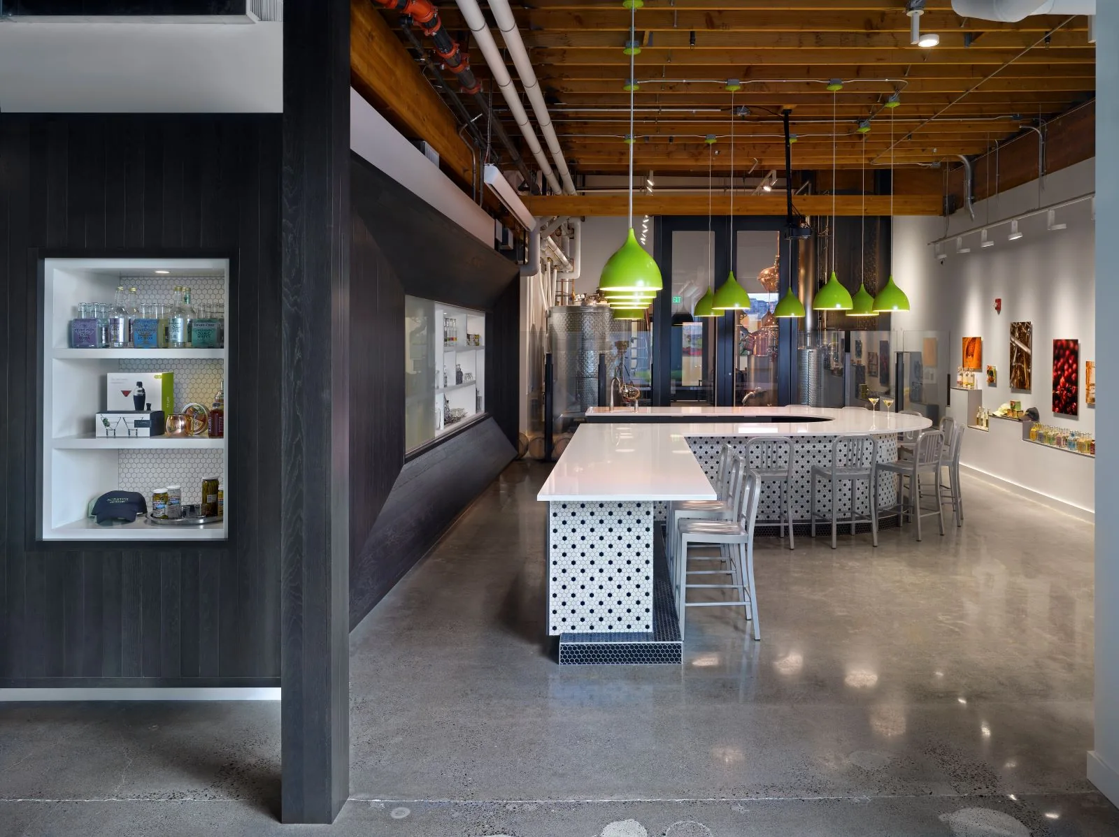 Modern tasting room featuring a curved white bar, vibrant green pendant lights, and polished concrete floors.