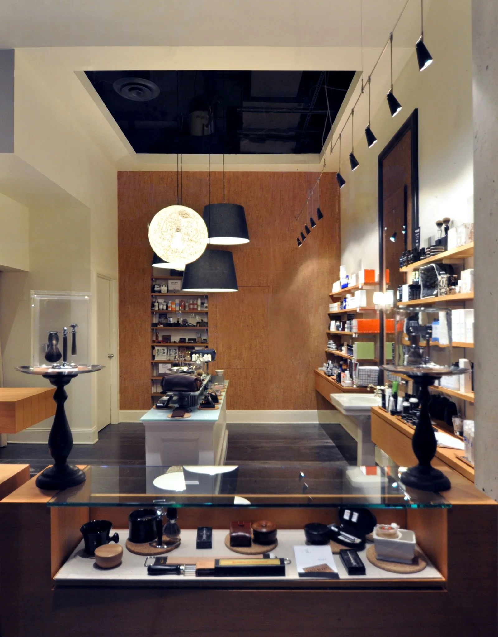 Modern grooming boutique interior with warm wood paneling, glass display cases, and contemporary lighting.